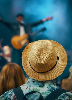 man with guitar standing on stage in front of crowd
