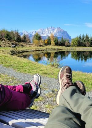 a couple of people sitting on a bench next to a lake