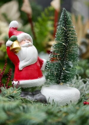a santa clause figurine next to a christmas tree