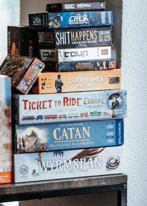 Board games are stacked on a shelf.